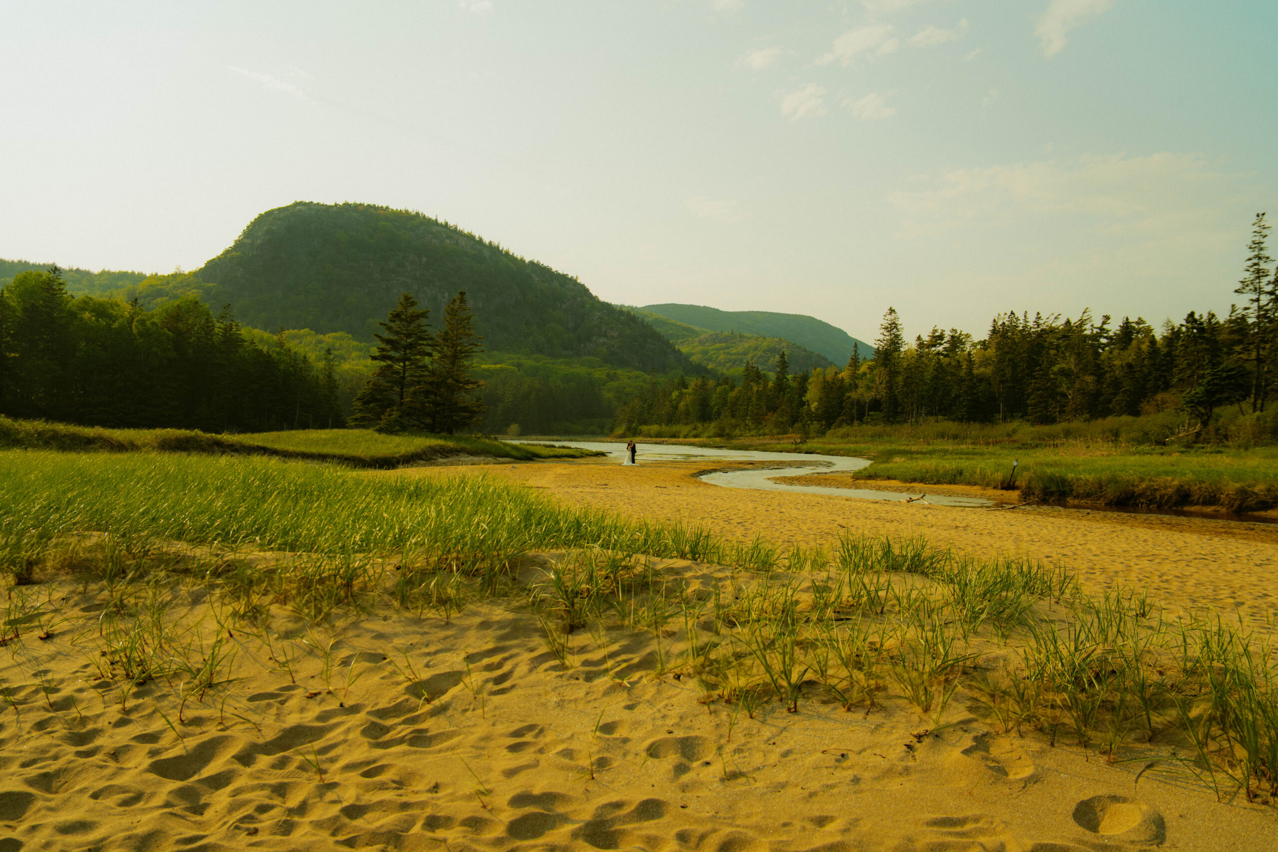 Bride and groom getting married on the beach with mountains behind them